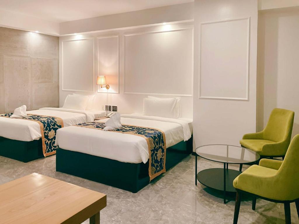 安吉利斯Hevea Hotel & Resort的酒店客房带两张床和一张桌子以及椅子。