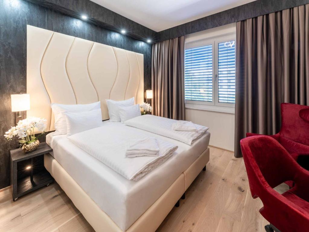 维也纳新城PLAZA INN Wiener Neustadt, BW Signature Collection的卧室配有一张白色大床和红色椅子
