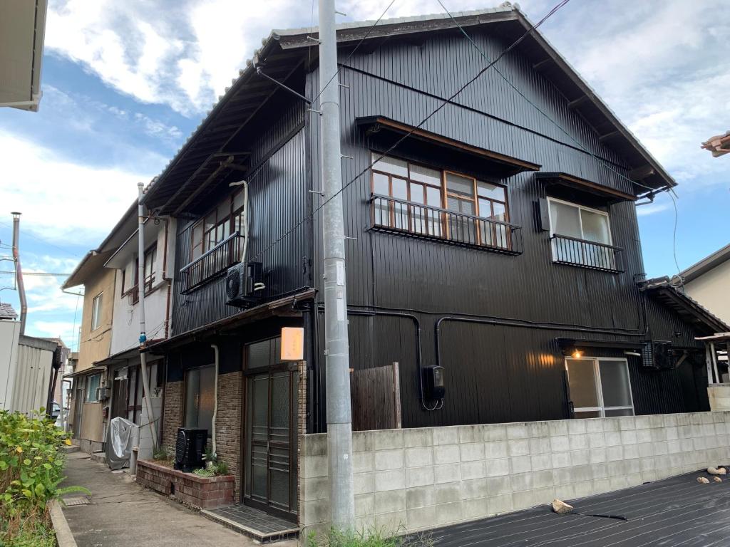 尾道市つばめ荘 Tsubamesou的前面有一根杆子的黑色房子