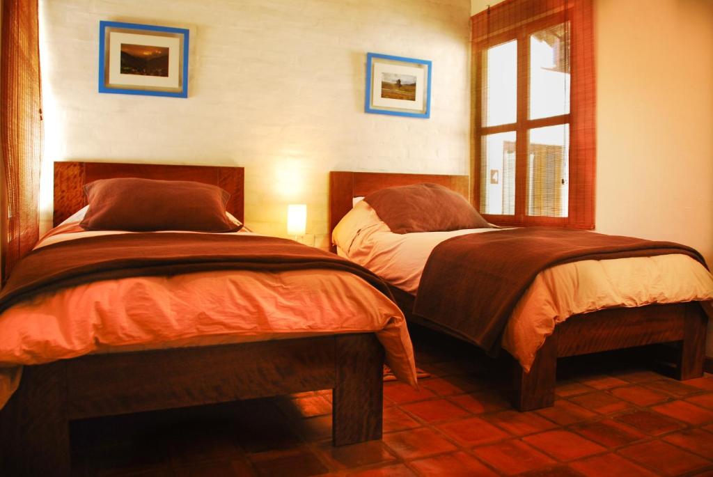 库斯科Kutty Wasi的一间卧室设有两张床和窗户。