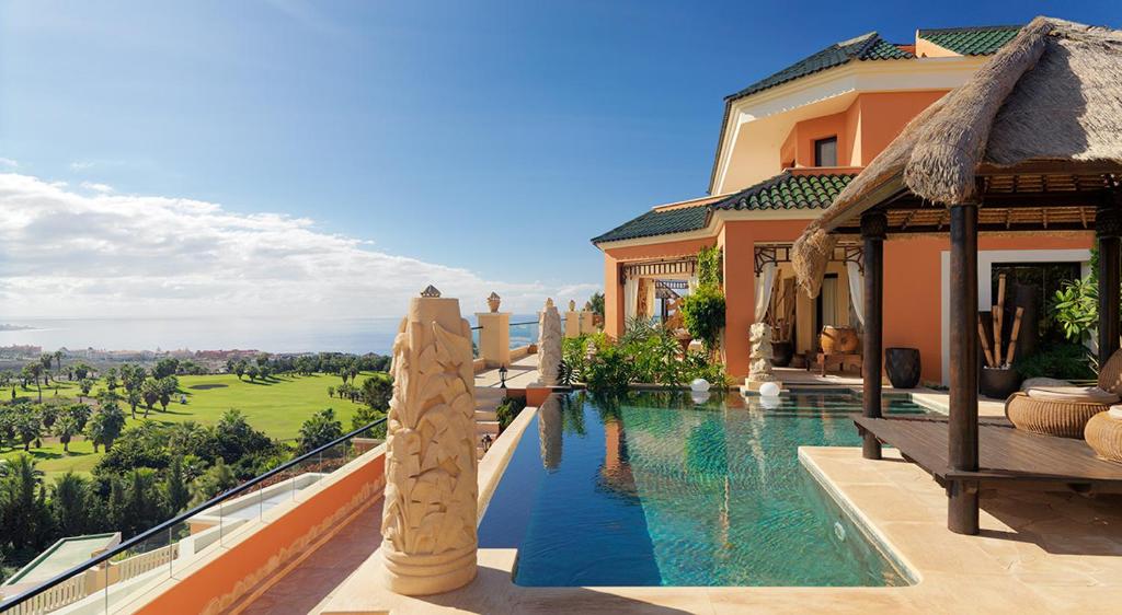 阿德耶Royal Garden Villas, Luxury Hotel的别墅毗邻一座房子,设有游泳池