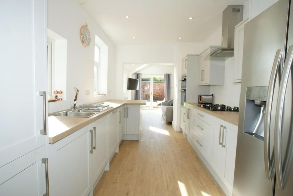 切斯特Modern 4 bed house near city centre/Chester Zoo的厨房铺有木地板,配有白色橱柜。