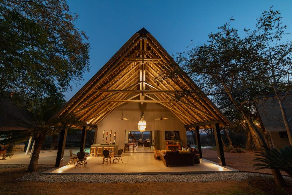 侯斯普瑞特Tomo Safari Lodge的一座带三角形屋顶的大型建筑,配有桌椅