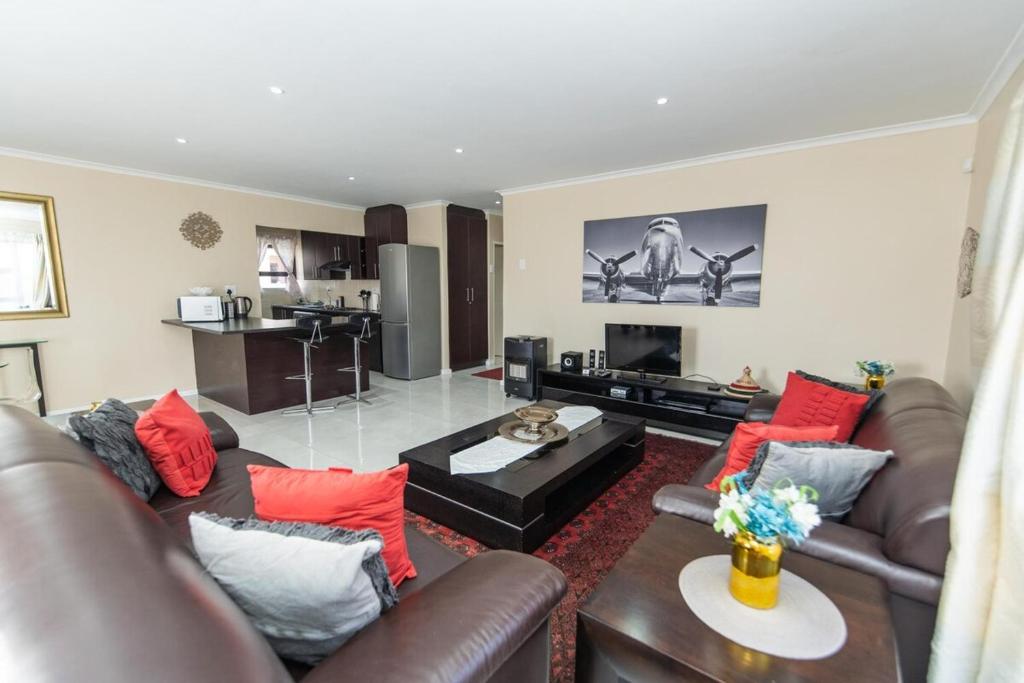 AmsterdamhoekCosy Home In Bluewater Bay的客厅配有棕色皮革家具和红色枕头。