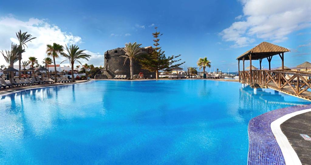 卡勒达德福斯特Barceló Fuerteventura Castillo的一个带凉亭和棕榈树的大型蓝色游泳池