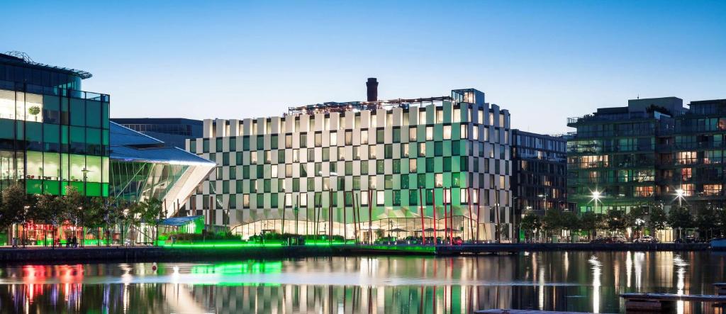 都柏林Anantara The Marker Dublin- A Leading Hotel of the World的一座大型玻璃建筑,毗邻一条河,有建筑