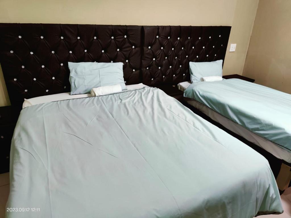 MtubatubaKang B&B的配有白色床单的酒店客房内的两张床