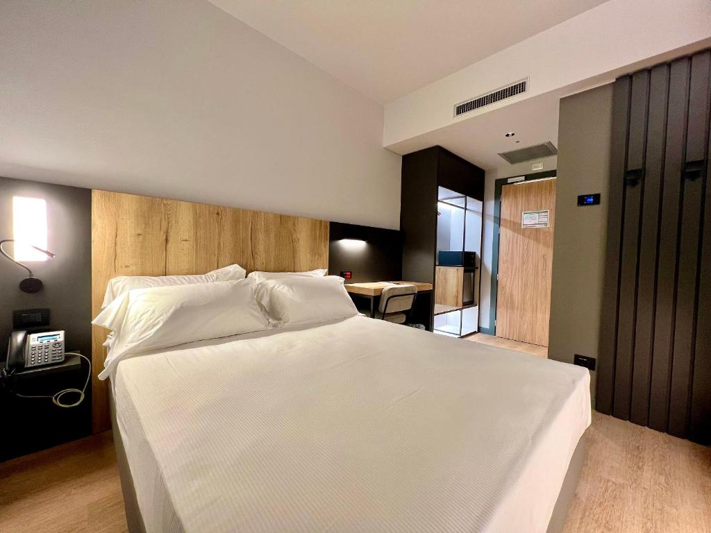 布雷西亚Hotel Leonessa的卧室配有一张白色的大床和电话