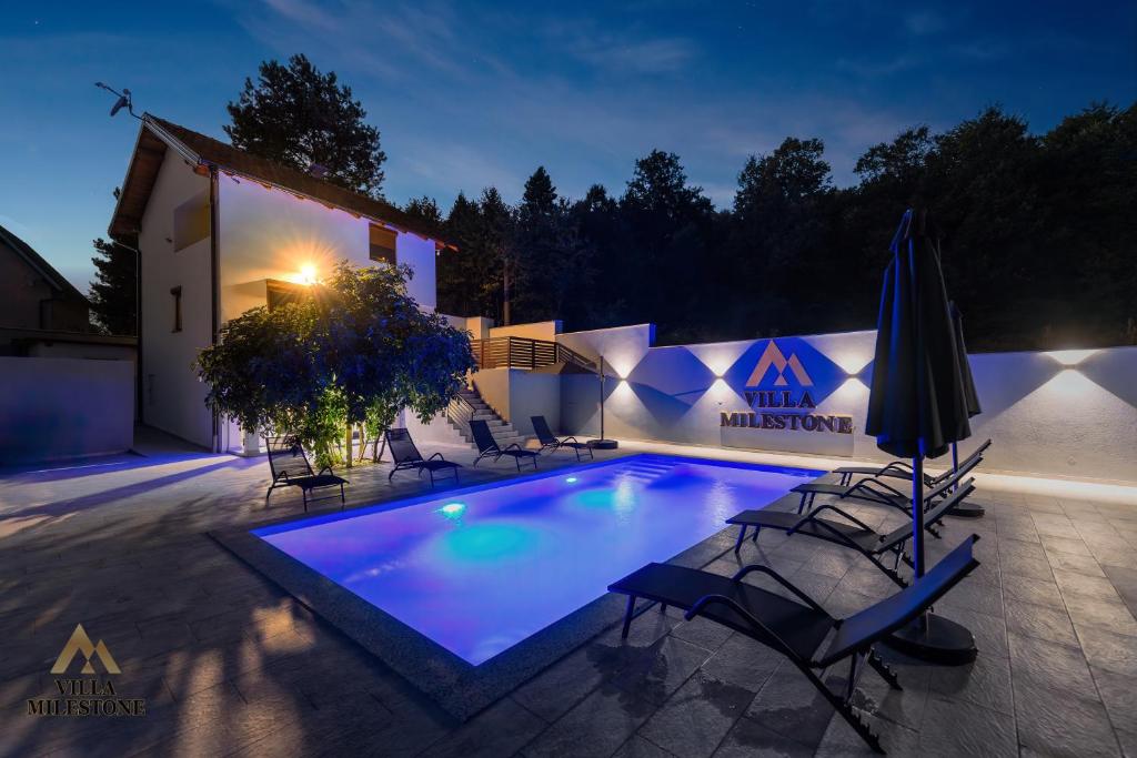 Villa Milestone Majevica的夜间在房子前面的游泳池