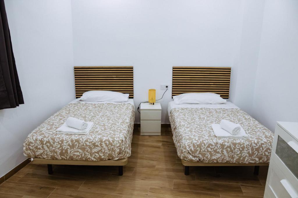 塞维利亚Triana Riverside Guesthouse的配有白色墙壁和木地板的客房内的两张床