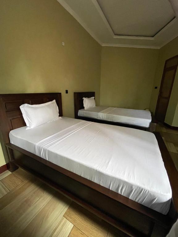阿鲁沙Skill forest lodge的一间卧室配有两张带白色床单的床