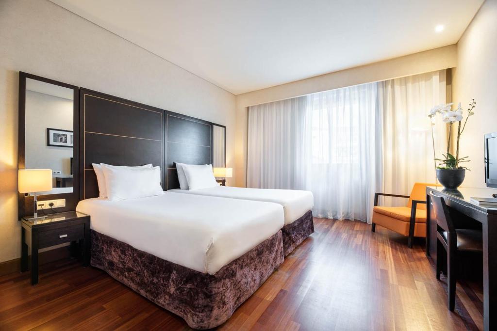 波尔图Eurostars das Artes的酒店客房设有一张大床和一张书桌。