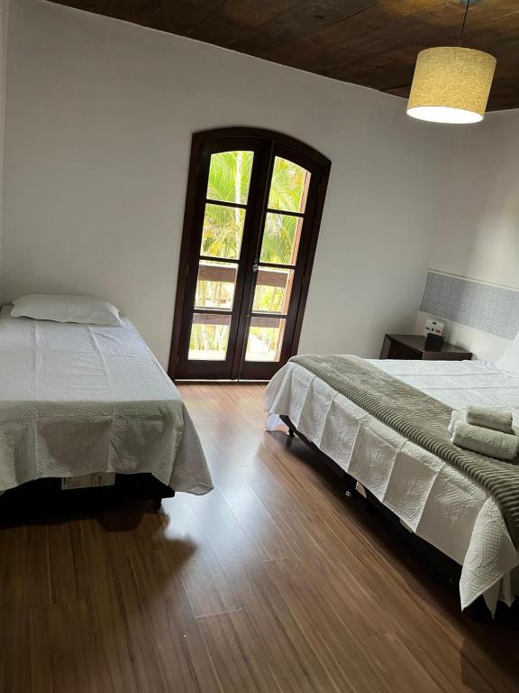 彼得罗波利斯Pousada Recanto Aurora的一间卧室设有两张床和窗户。