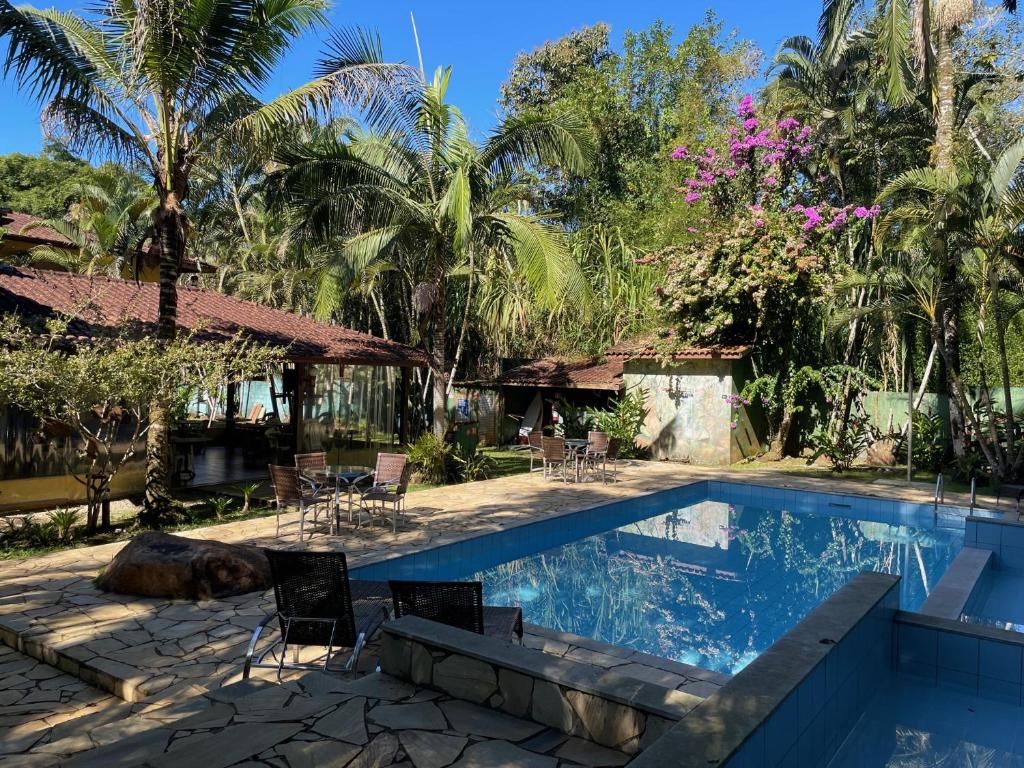 乌巴图巴Canto de Itamambuca的度假村的游泳池,带椅子和树木