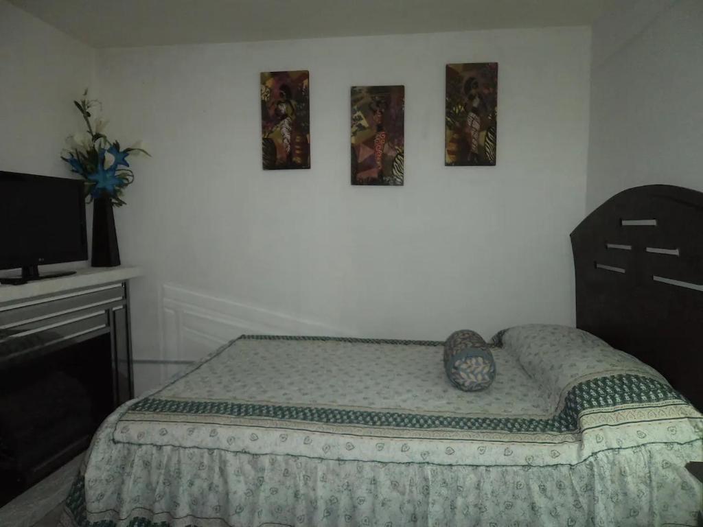 库斯科Q'entiHospedaje zaguan del cielo 2的卧室配有一张床,墙上挂有两张照片