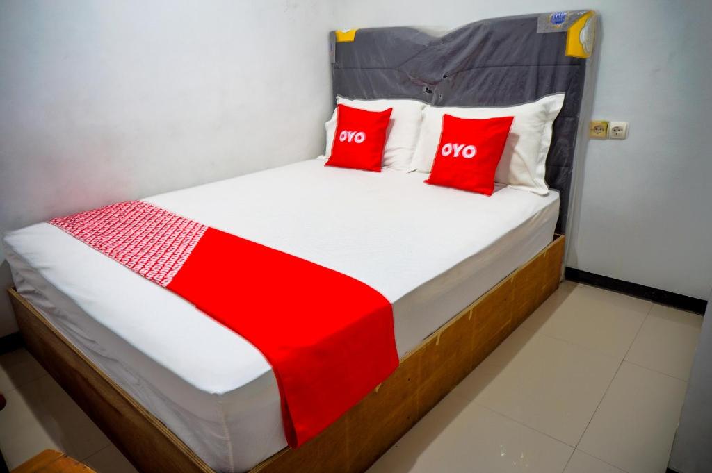 泗水OYO 93069 Penginapan Sumber Rizki的宿舍间内的一张床位,上面有红色枕头