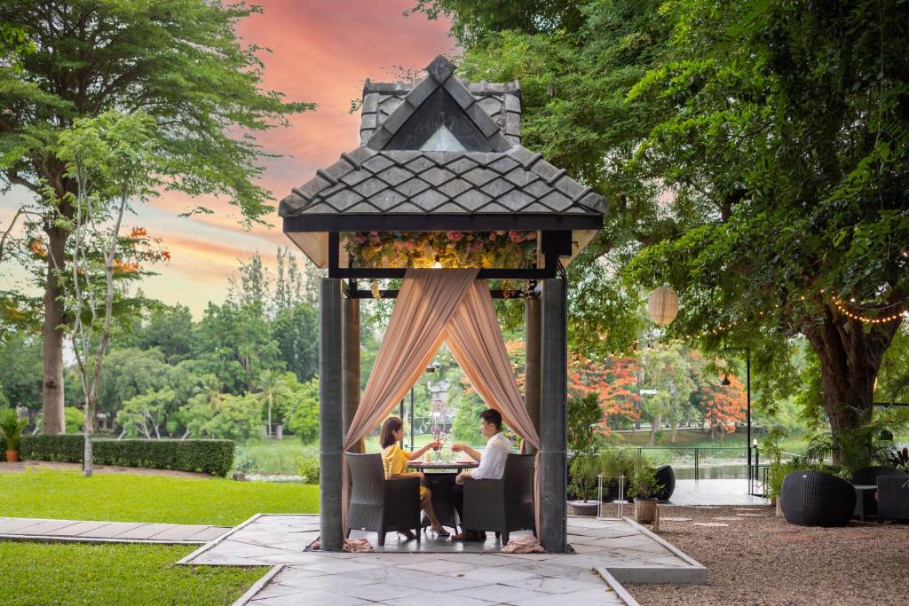 北碧U Inchantree Kanchanaburi的两人坐在凉亭的桌子上