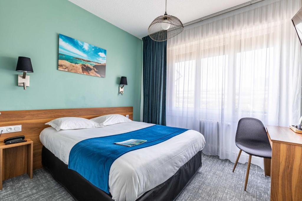 雷恩le paris brest hotel的酒店客房配有一张床、一张桌子和一把椅子。