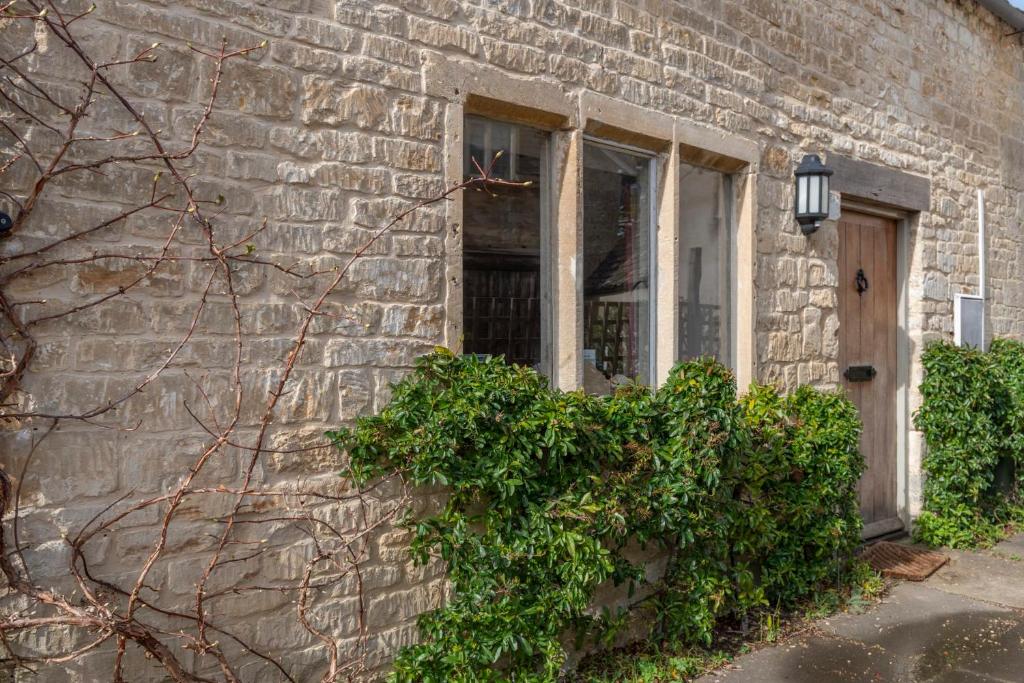 斯特劳德Traditional Cotswold Stone Peaceful Cottage with stunning views的砖砌的建筑,有门和窗户