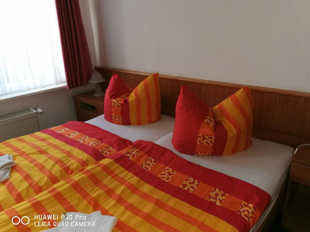 KölledaPension Am Stadion的一间卧室配有红色和黄色枕头的床