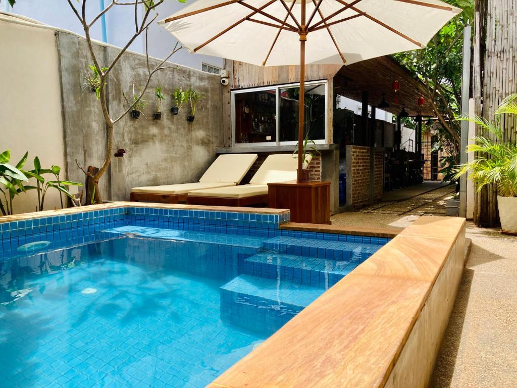 暹粒Lotus Haven Villa的一个带遮阳伞和长凳的游泳池