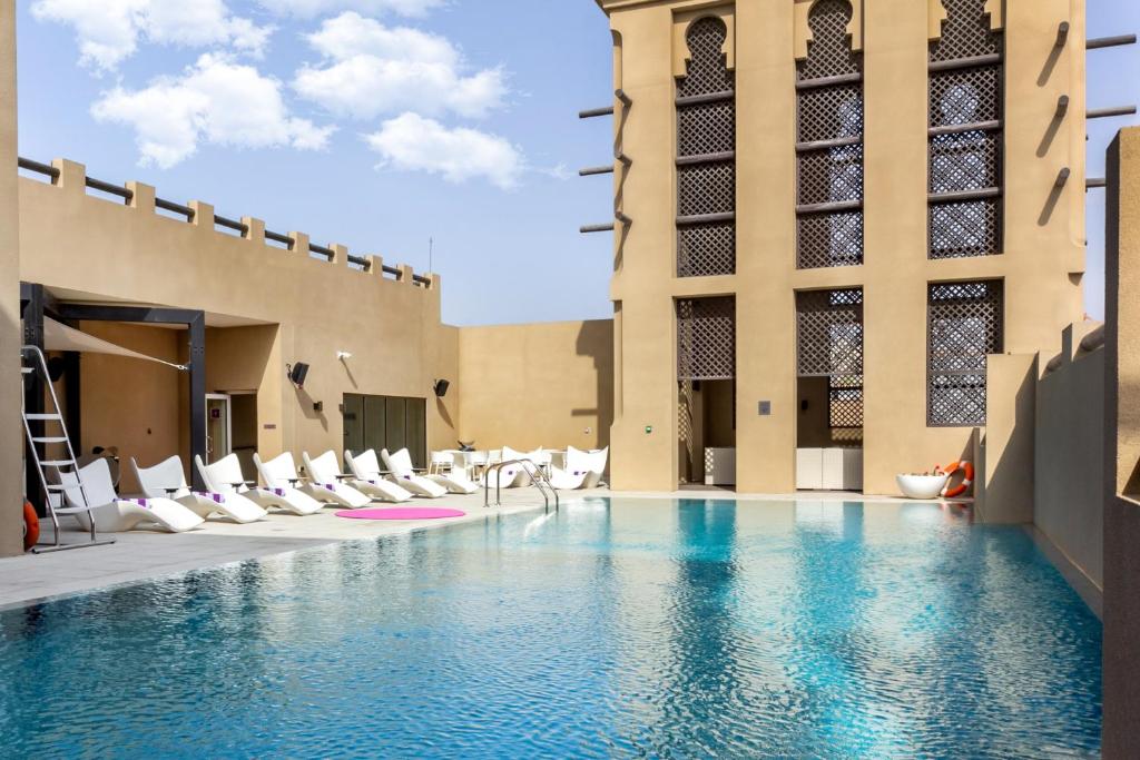 迪拜Premier Inn Dubai Al Jaddaf的一座带白色躺椅的游泳池