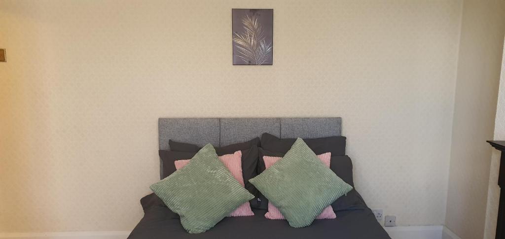 考文垂Coventry Spacious Rooms In City的一间卧室配有带绿色和粉红色枕头的床