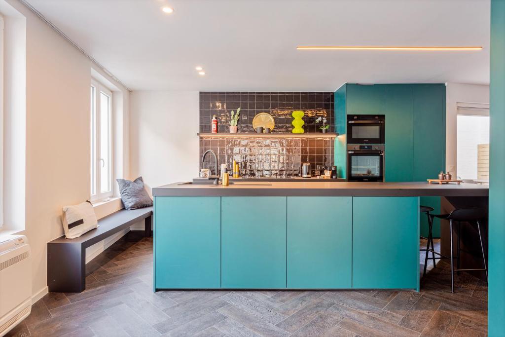 梅赫伦Uma's Urban Lounge的厨房配有绿松石橱柜和柜台。