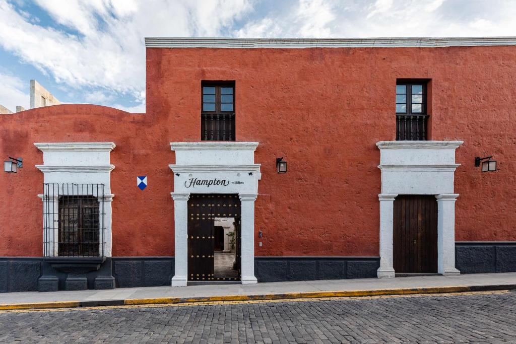 阿雷基帕Hampton by Hilton Arequipa的红砖建筑,有白色的柱子和门廊