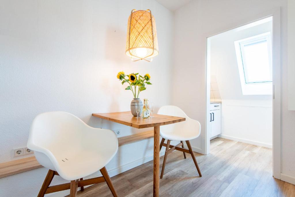 兰图姆Steger-Hüs Wohnung 26的一间带桌子和两把白色椅子的用餐室