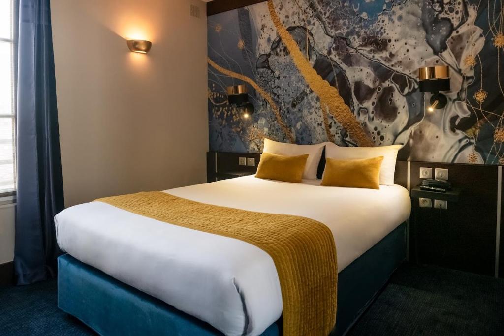 巴黎Hôtel du Parc Montparnasse的酒店客房配有一张带黄色枕头的大床