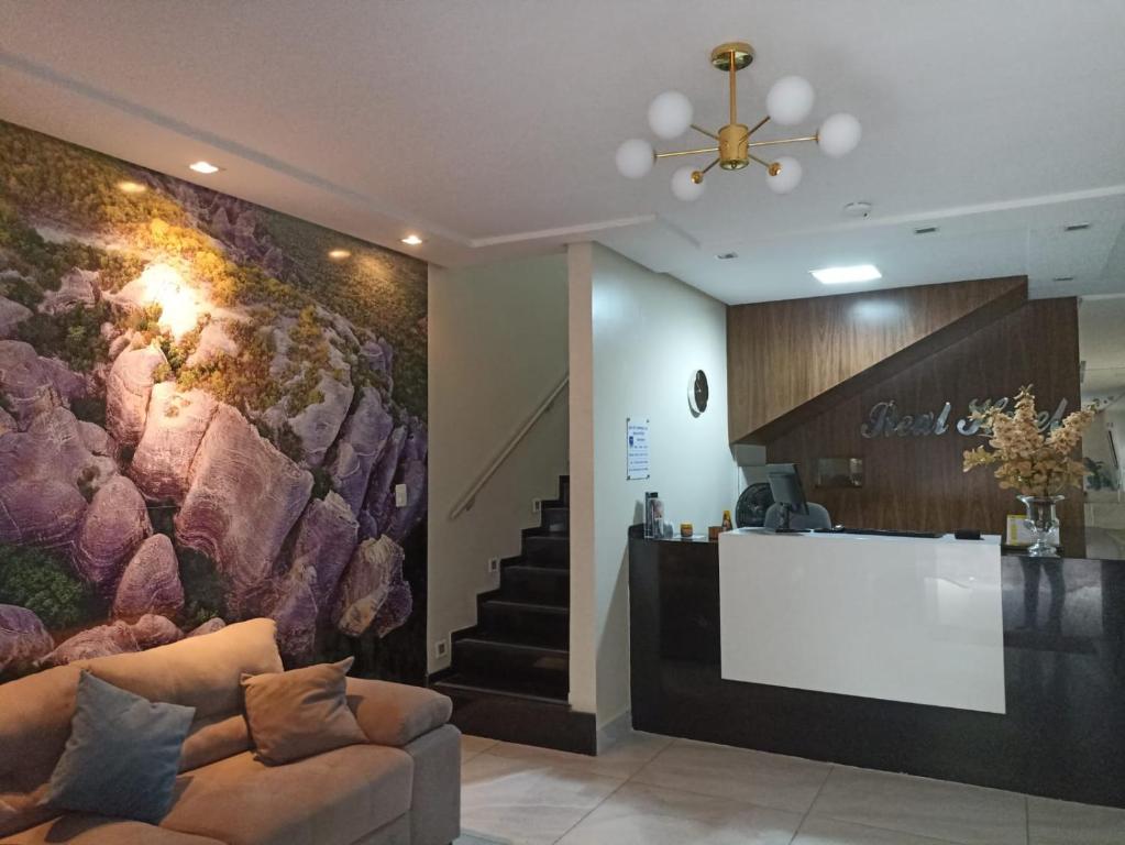 圣雷蒙多-诺纳图Real Hotel Empreendimentos的大堂配有沙发、柜台和楼梯。