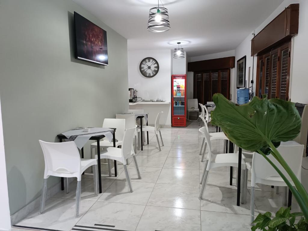 特尔马斯德里奥翁多Hotel FG的餐厅设有白色椅子和墙上的时钟