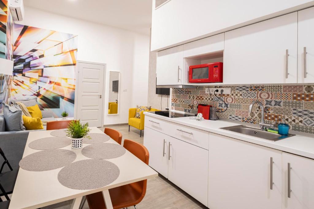 布达佩斯Klauzal Bella Apartment的厨房配有白色橱柜和桌椅