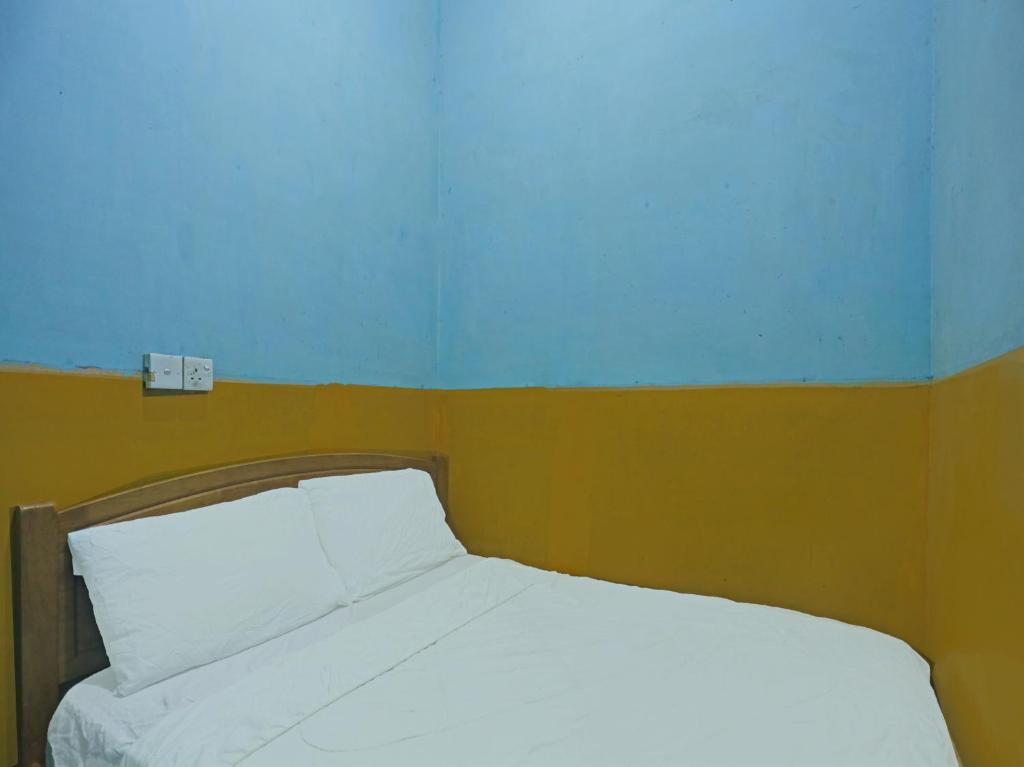 名古屋SPOT ON 92985 Mitra Homestay的卧室配有白色床和蓝色墙壁