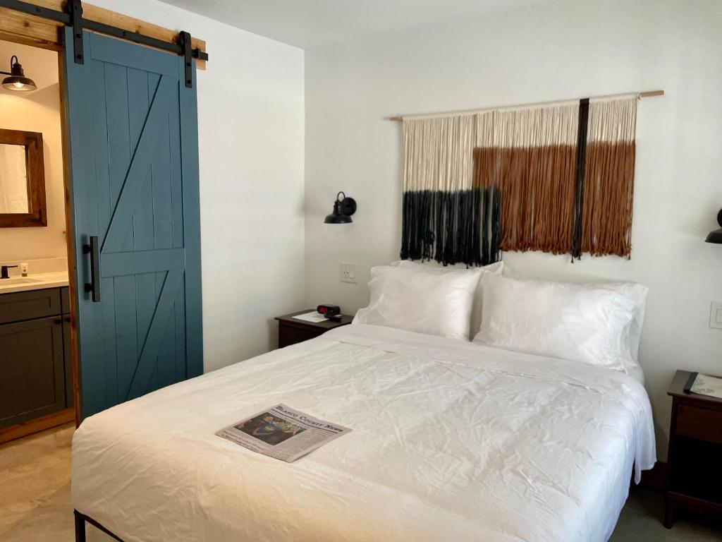 BlancoBlanco County Inn & Guesthouses的卧室配有白色的床和蓝色的门