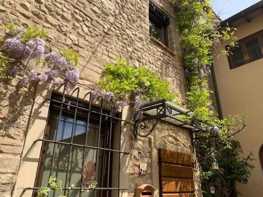 比森齐奥营casatorre medioevale的一座建筑,上面有紫色花朵的窗户