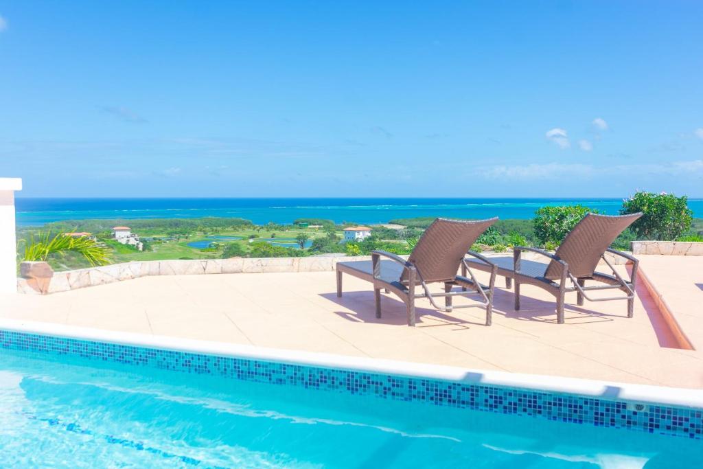 罗阿坦Pristine Bay 1303 villa的一个带两把椅子的游泳池,背景是大海