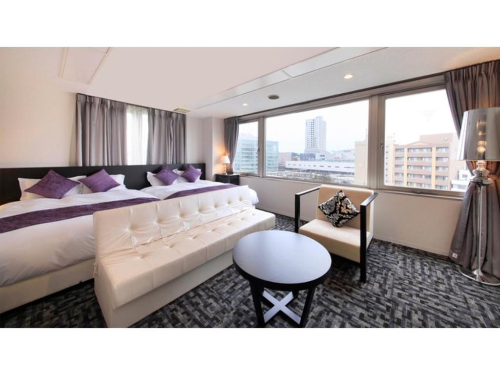 福井Centurion Hotel Villa Suite Fukui Ekimae - Vacation STAY 34532v的酒店客房配有一张带紫色枕头的大床