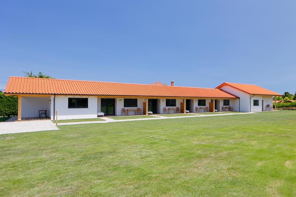 库迪列罗Apartamentos Aronces的一座白色的建筑,有橙色的屋顶和草地