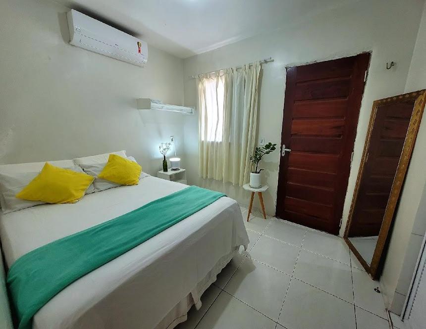 福塔莱萨Teto Hospedagens的一间卧室配有一张大床,提供黄色和绿色的枕头