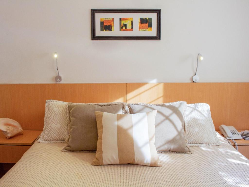 埃斯特角城阿贾克斯酒店的一张带白色枕头的床和一张墙上的照片