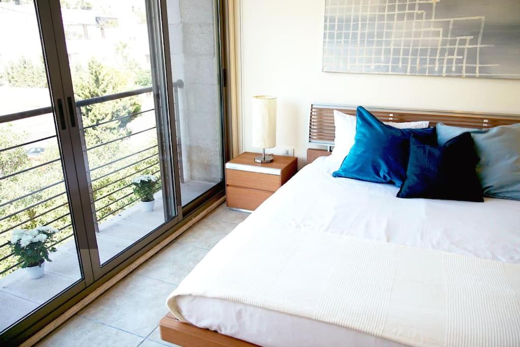 安曼Sleek & Cozy Apartment with Pool & Patio In Abdoun的一间卧室配有一张带蓝色枕头的床和一扇窗户。