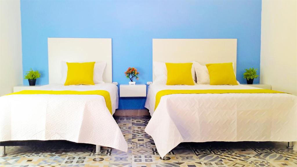 圣玛尔塔Believer Hostel的蓝色客房内的两张床和黄色枕头