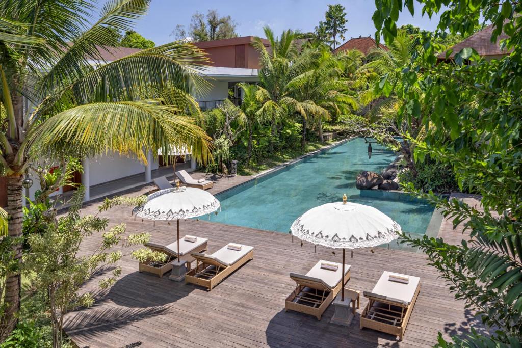乌布The Hava Ubud A Pramana Experience的享有带遮阳伞和椅子的度假村游泳池的空中景致