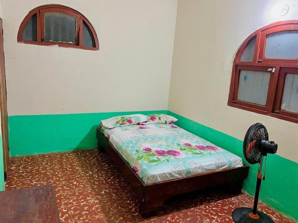 莱昂Rainbow House的配有风扇的客房内的一张小床