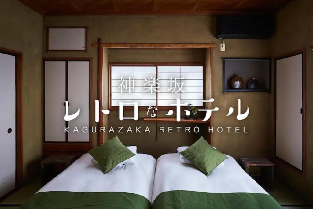 东京Kagurazaka Retro BAR & HOTEL的墙上有标牌的房间的两张床