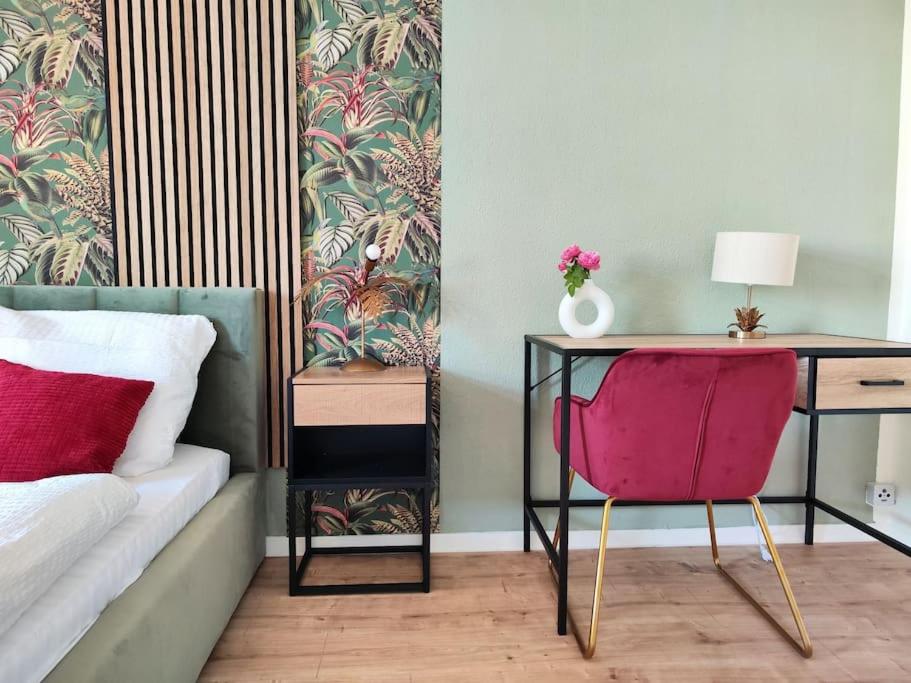 德累斯顿tealounge 2 Raum + Küche的一间卧室配有书桌和一张带粉红色椅子的床。