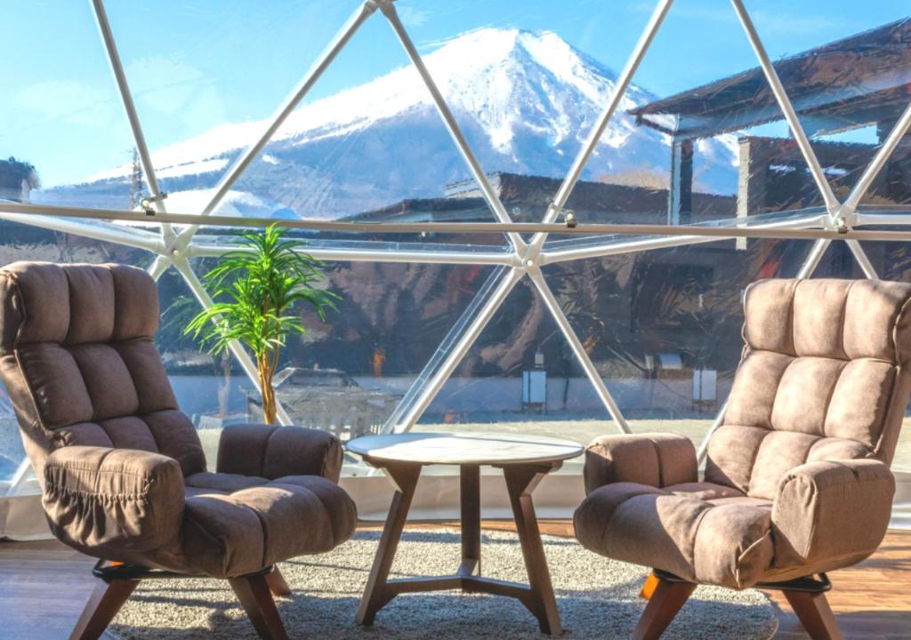 山中湖村VISION GLAMPING Resort & Spa 山中湖 ビジョングランピングリゾート山中湖的窗前的两把椅子和一张桌子