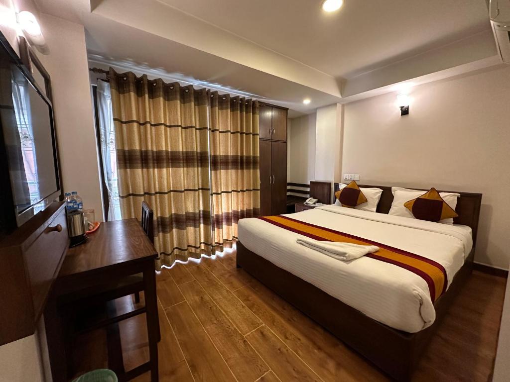 加德满都尼泊尔珠峰酒店的酒店客房设有一张大床和一张书桌。